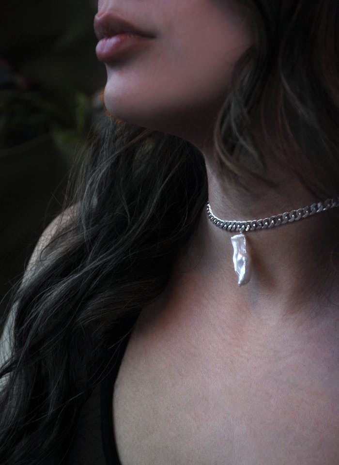 Close-up of a silver pendant necklace worn by a woman, showcasing fine jewelry and fashion.